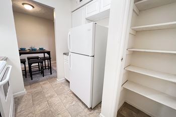 A white refrigerator in a kitchen with a table and chairs.
